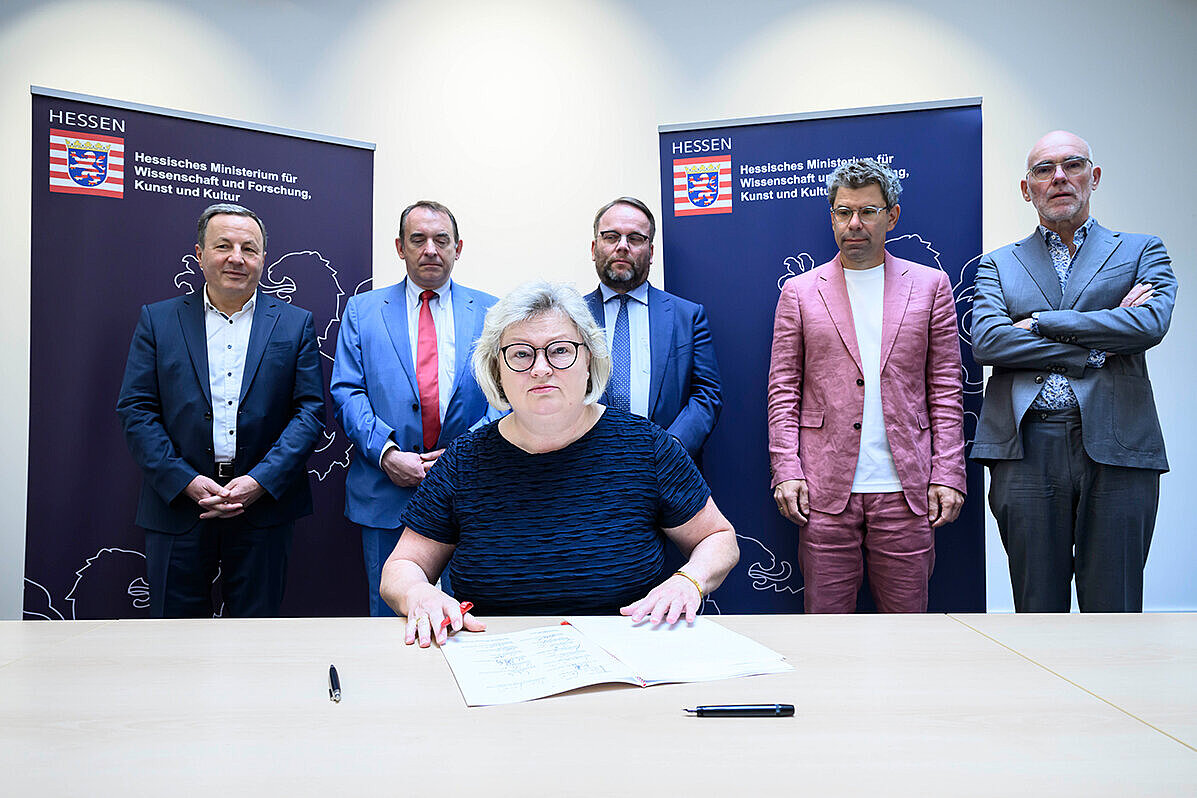 Unterzeichnung Hessischer Hochschulpakt Prof Dr. Eva Waller sitzt an einem Tisch, auf dem der Hochschulpakt liegt. Hinter ihr stehen Prof. Dr. Karim Khakzar, Prof. Dr. R. Alexander Lorz, Timon Gremmels, Prof. Dr. Thomas Nauss, Prof. Elmar Fulda