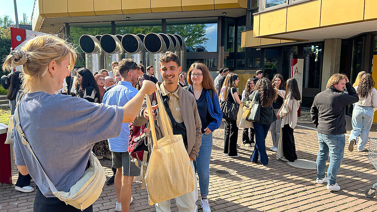 Erstsemesterbegrüßung Sommersemester 2025 Vertreter:innen des AStA stehen auf dem Campus Kurt-Schumacher-Ring und verteilen die beliebten Ersti-Taschen.