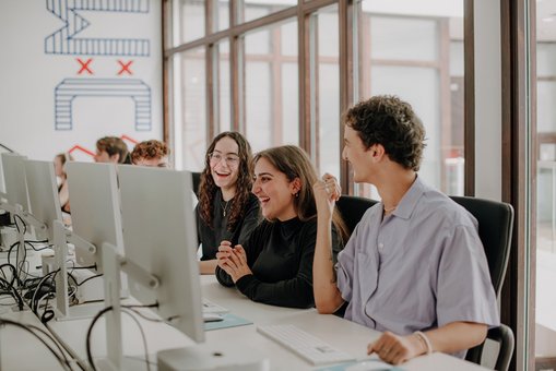 Students sitting at desks and looking at computer monitors 