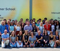 Gruppenfoto mit allen Beteiligten vor einer Werbeplakatwand für die Summer School.