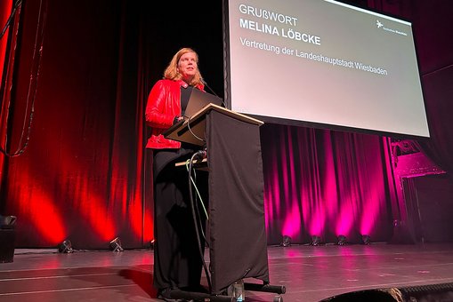 Milena Löbcke, Dezernentin für Gesundheit, Integration und Verbraucherschutz der Landeshauptstadt Wiesbaden, steht auf der Bühne des Schlachthofs und begrüßt die Studierenden.