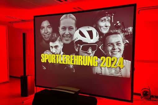 Blick auf die Leinwand mit einer Collage von Spitzensportler:innen der Hessischen Hochschule für öffentliches Management und Sicherheit und der Hochschule RheinMain, darüber der Text „Sportlerempfang 2024“