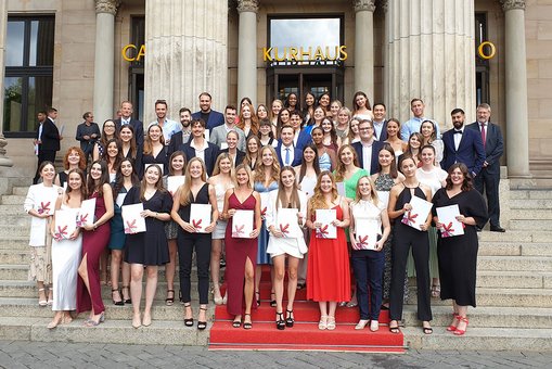 Gruppenfoto mit Absolvent:innen des Fachbereichs Wiesbaden Business School vor dem Kurhaus Wiesbaden