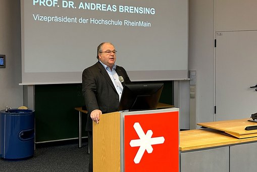 Prof. Dr. Andreas Brensing steht am Rednerpult des Audimax der Hochschule RheinMain